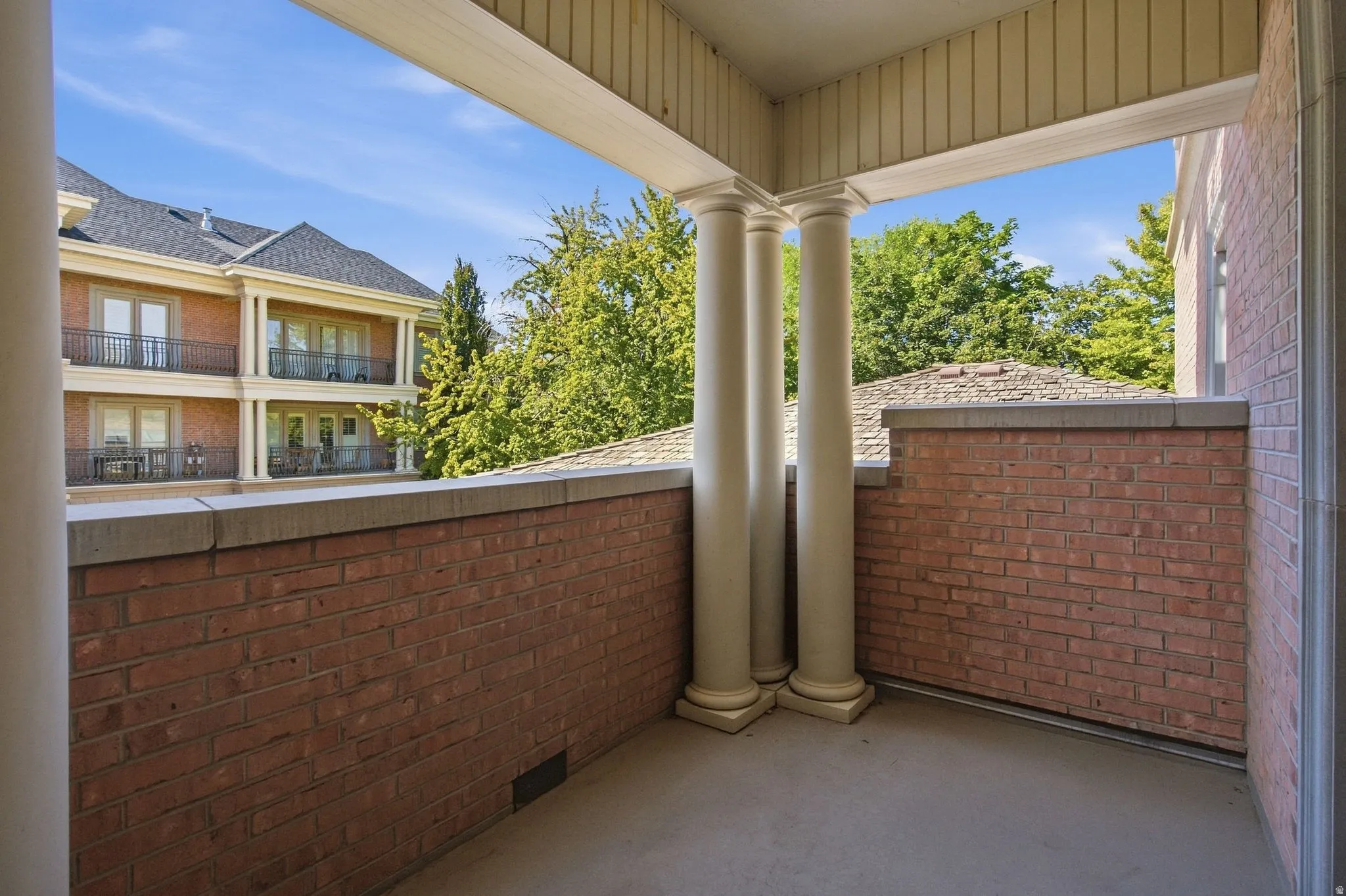 Private balcony featuring brick construction, decorative columns, and a concrete floor