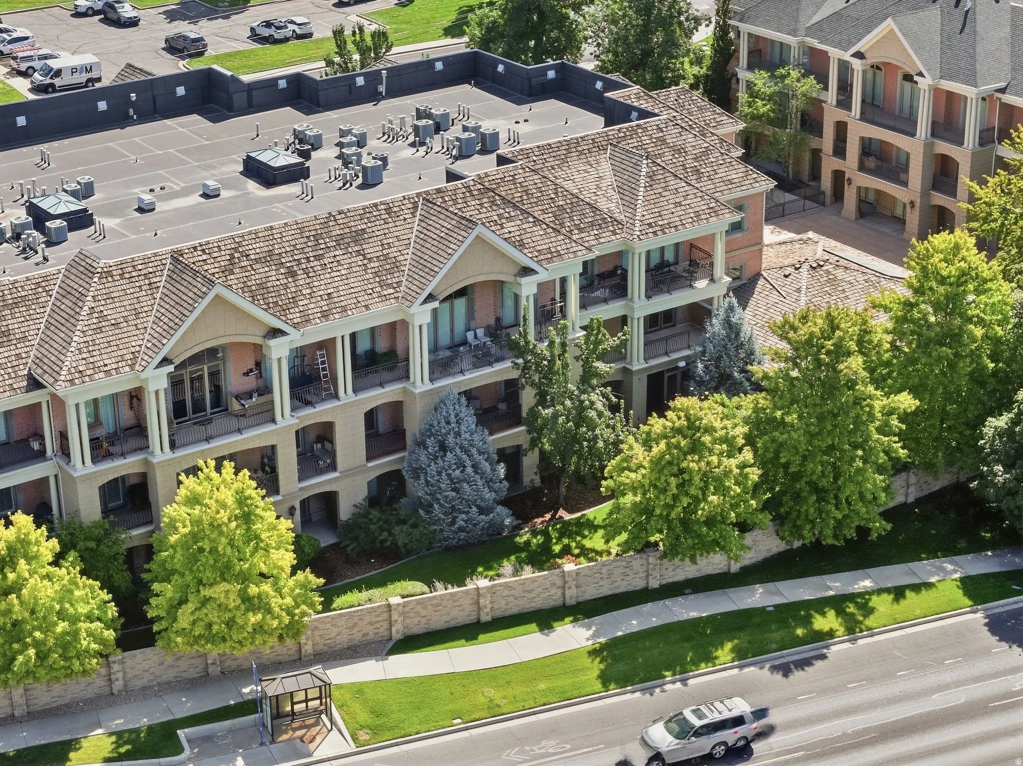 Multi-story building featuring balconies with wrought iron railings, a tiled roof, and light-colored exterior walls
