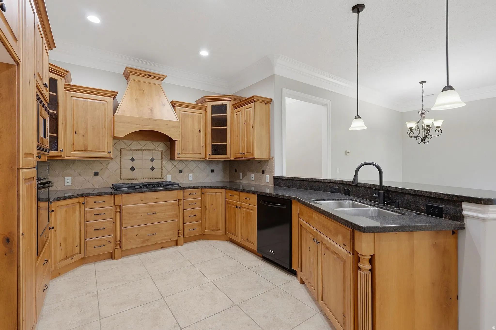 Kitchen featuring wood cabinetry, dark countertops, tile flooring, and stainless steel sink with matte black faucet