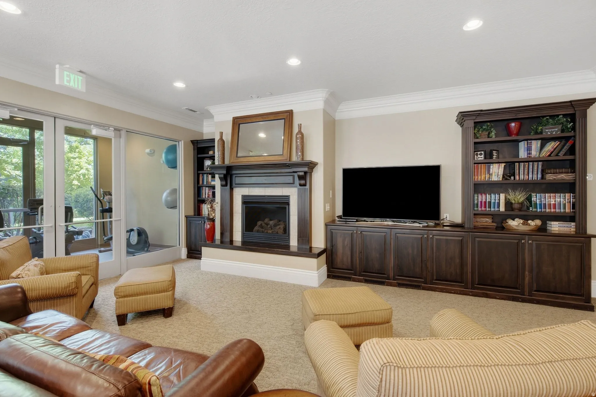 Built-in entertainment center with integrated shelving, fireplace with mantel and hearth, recessed ceiling lighting, and crown molding