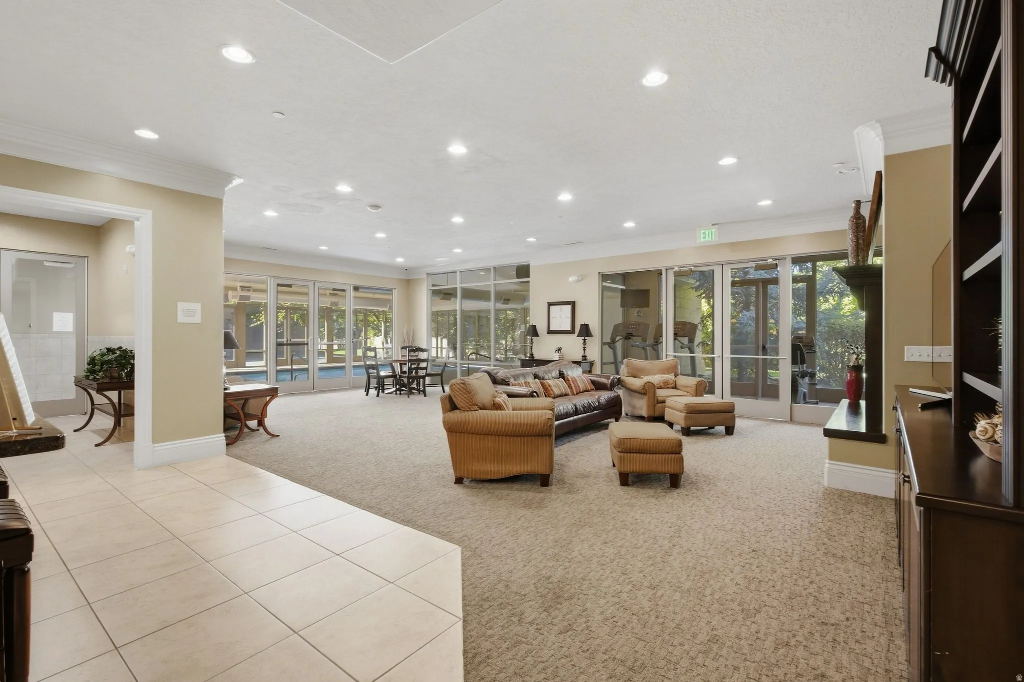 Expansive common area featuring recessed lighting, large format tile flooring, and direct access to an outdoor pool area through multiple glass panel doors