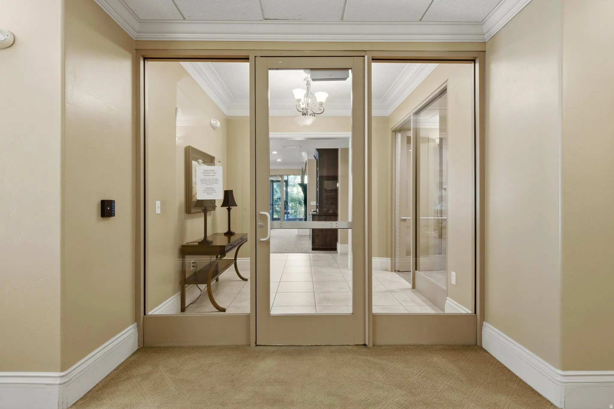 Glass-paneled entry doors with side panels, crown molding, and neutral wall tones