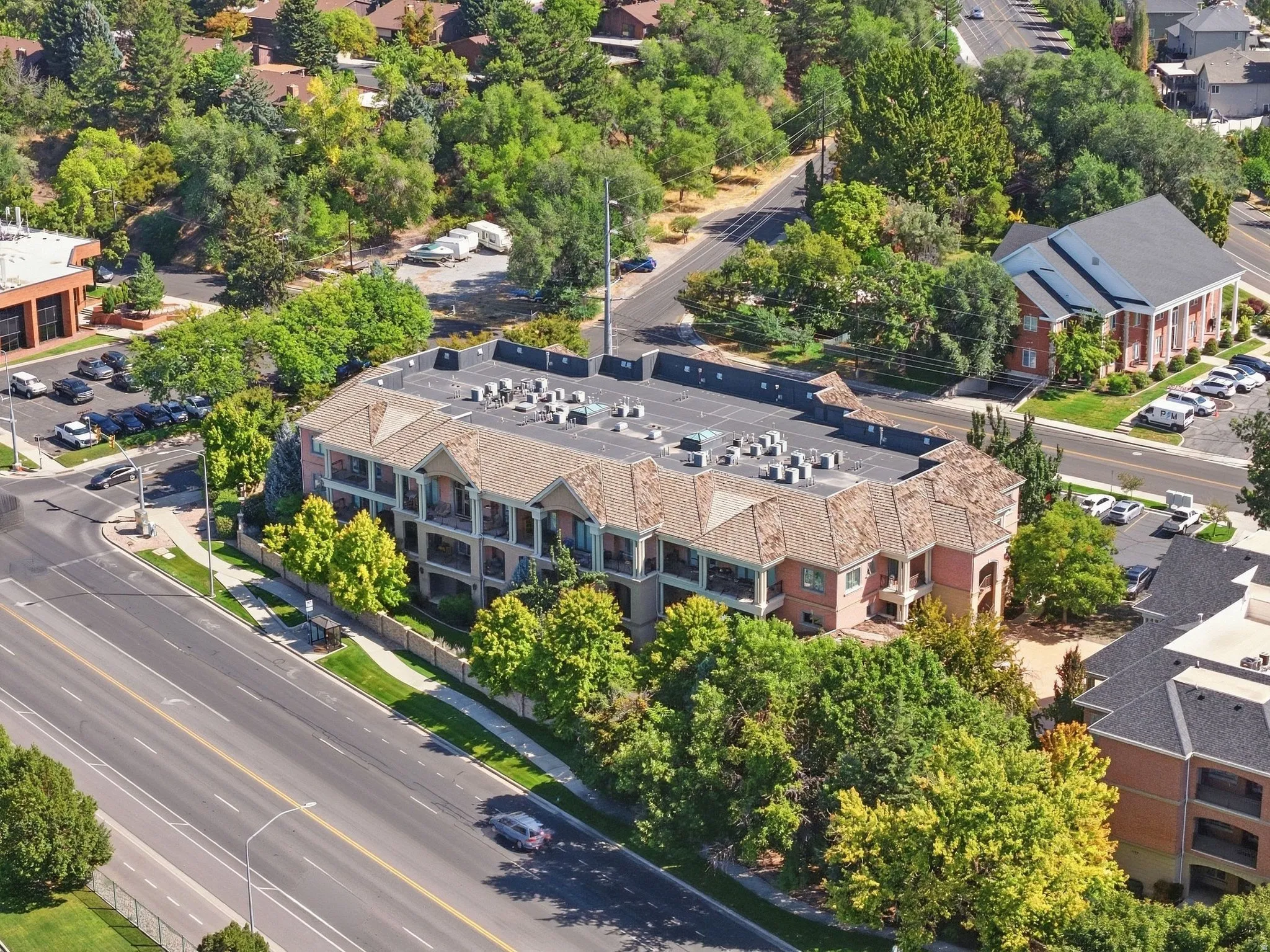 Multi-story building featuring balconies, a pitched roof, and visible rooftop units