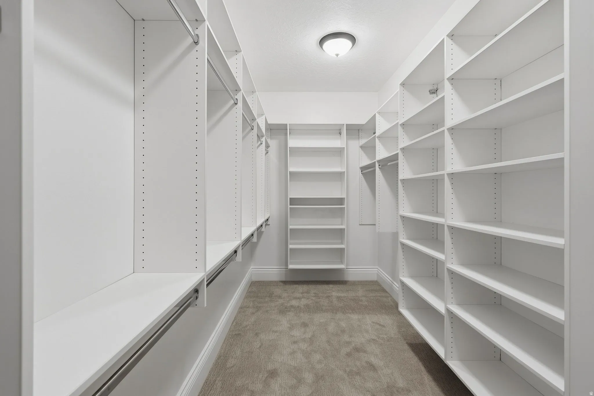 Expansive walk-in closet featuring built-in white shelving, integrated hanging rods, and carpeting