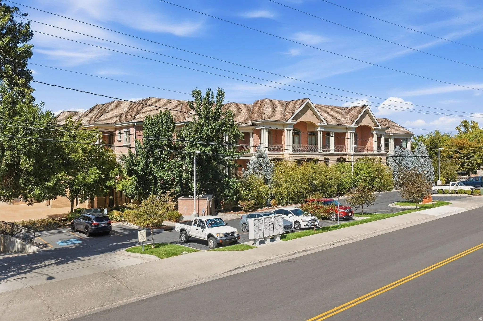 Brick facade building featuring multiple gabled roofs, a prominent portico entrance with columns, and a paved parking area