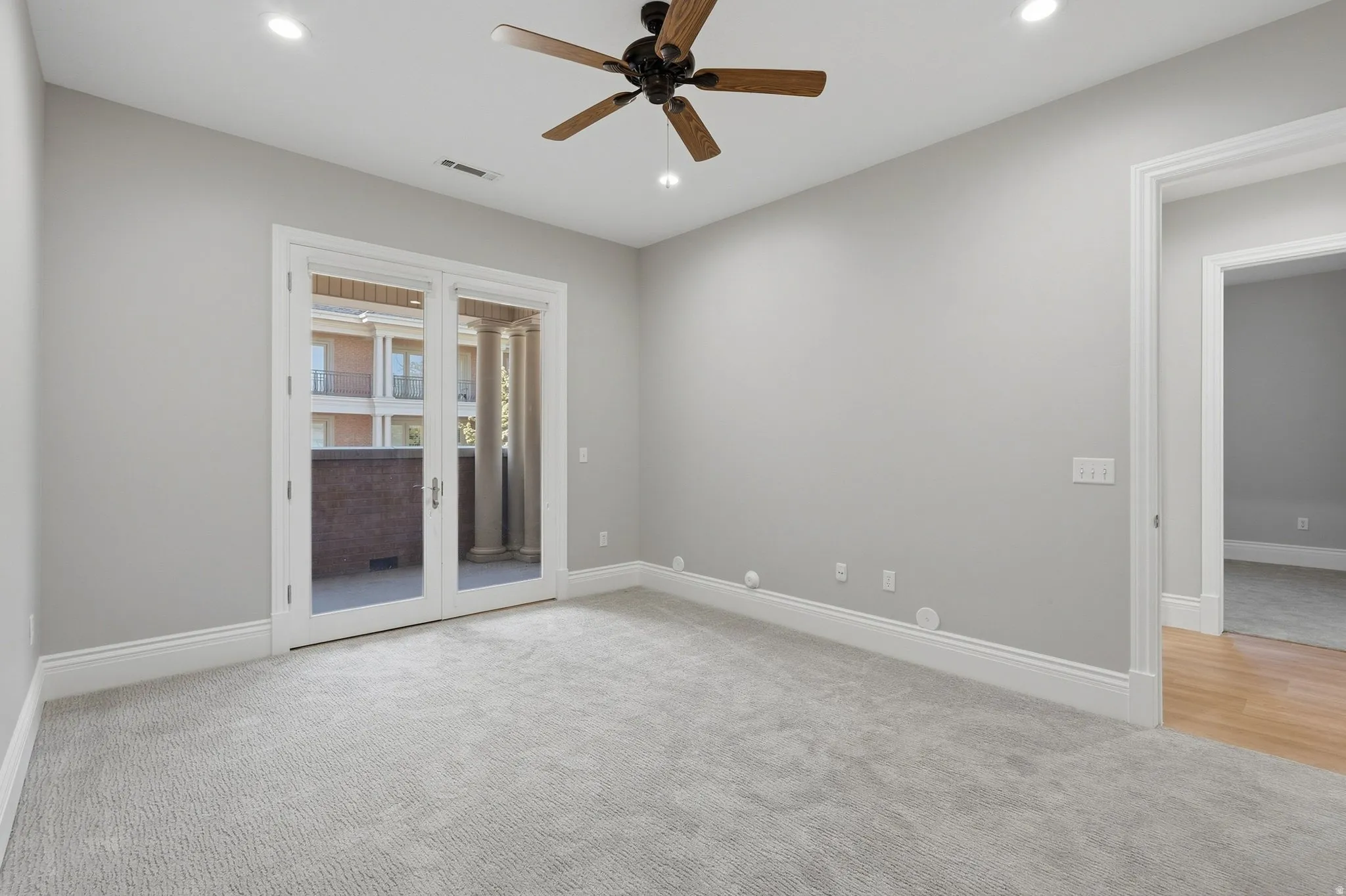 Recessed lighting, ceiling fan, double French doors, and light-toned carpeting