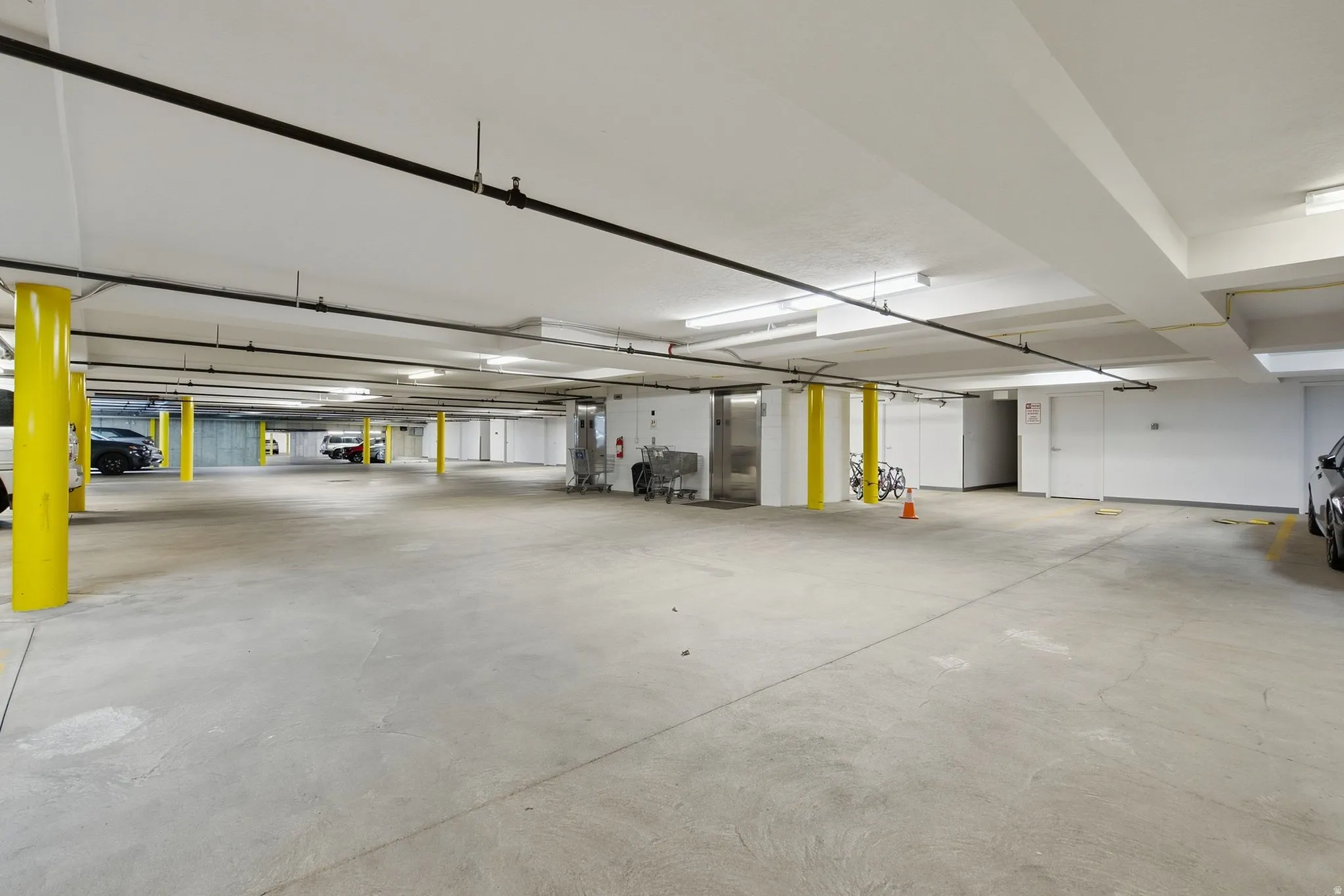 Underground parking garage featuring concrete flooring, structural support columns, and overhead lighting fixtures