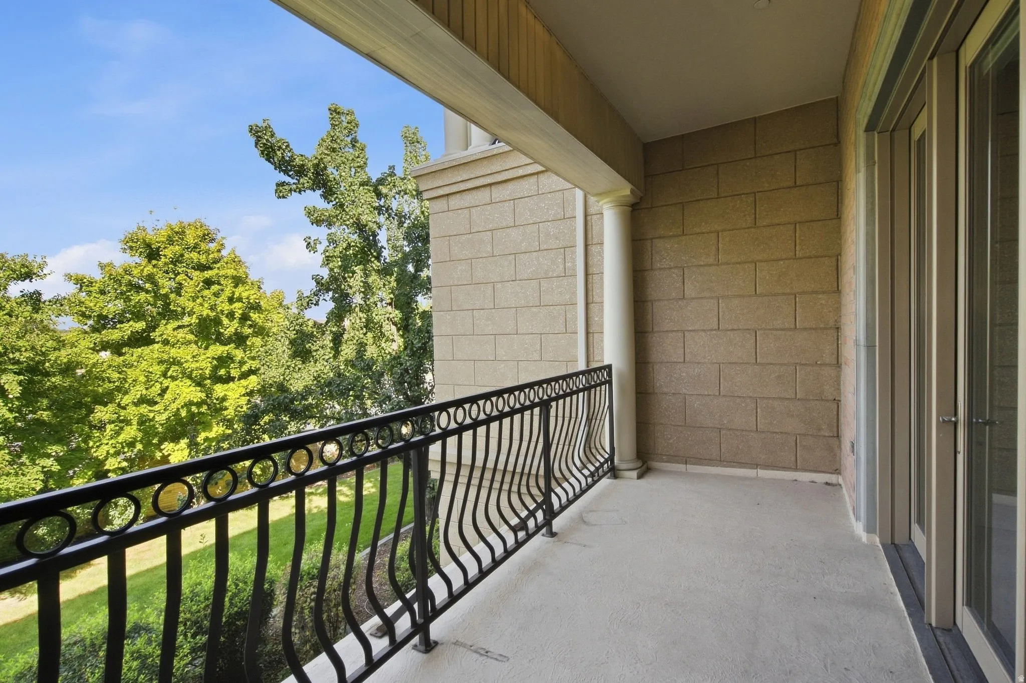 Balcony with a black wrought iron railing, light-colored block exterior, and glass panel doors