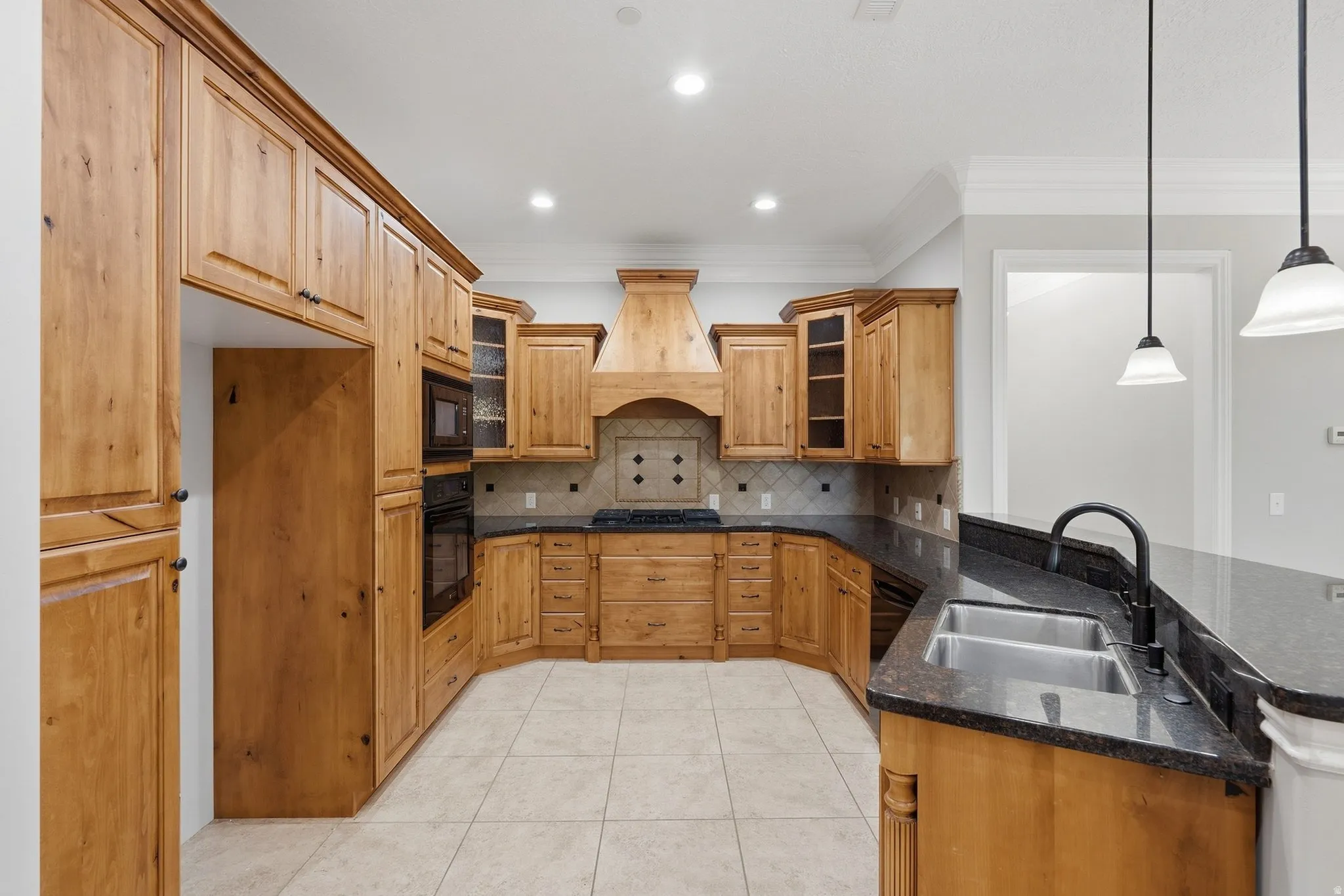 Kitchen featuring wood cabinetry, dark stone countertops, tile flooring, a double basin sink with a gooseneck faucet, and recessed lighting