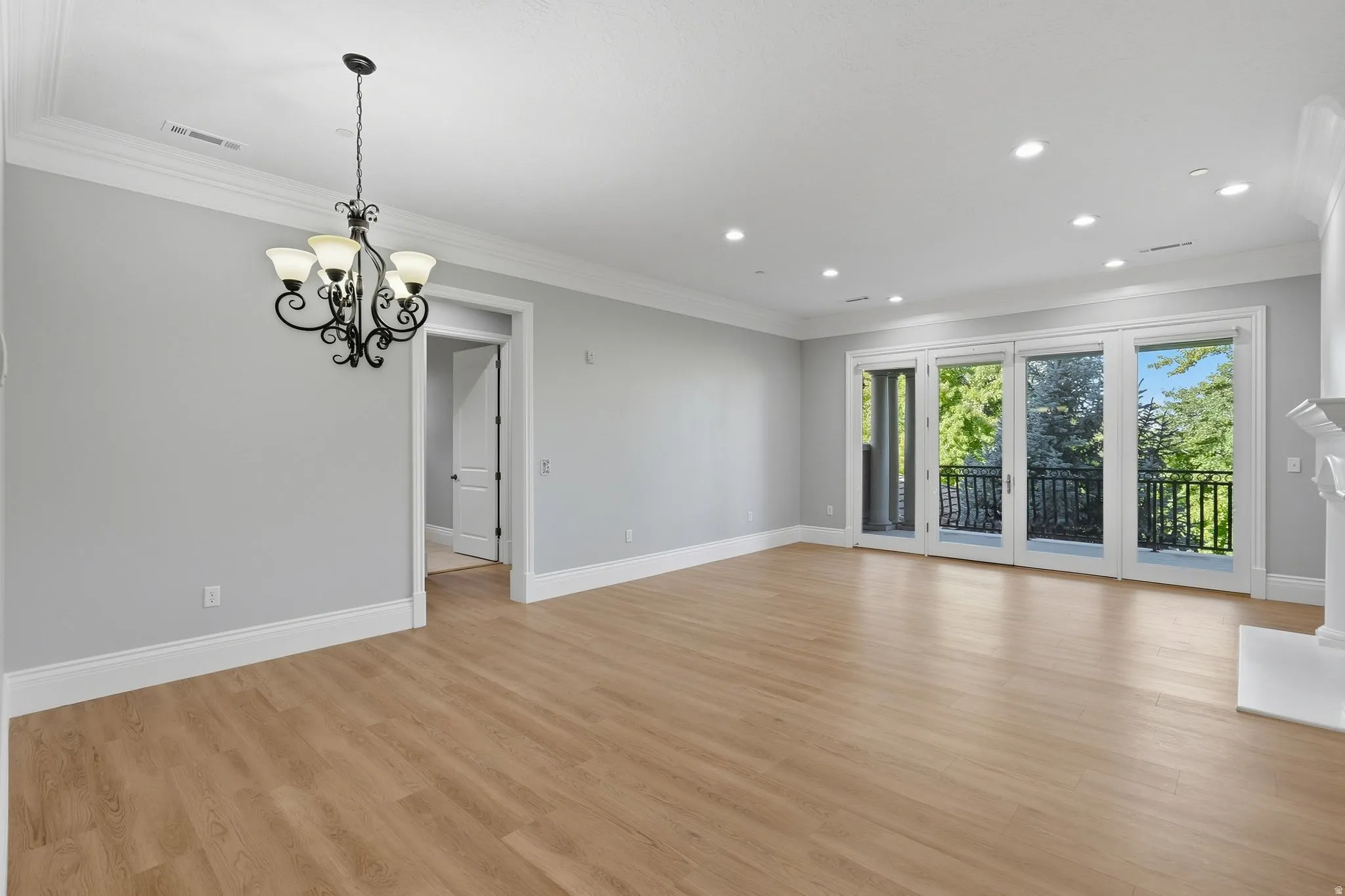Wood-finish flooring throughout, wrought iron chandelier, recessed lighting, crown molding, and a built-in fireplace