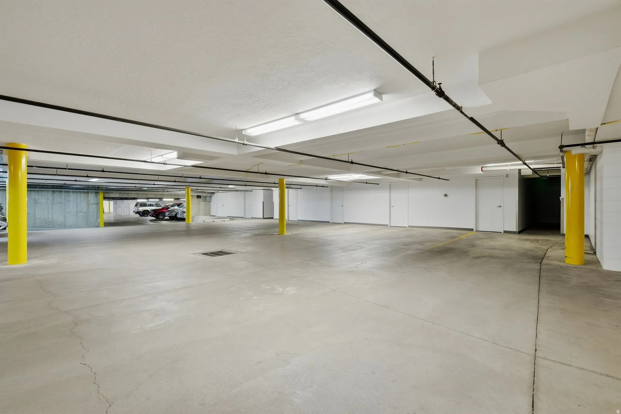 Concrete parking garage featuring bright yellow support columns and fluorescent overhead lighting