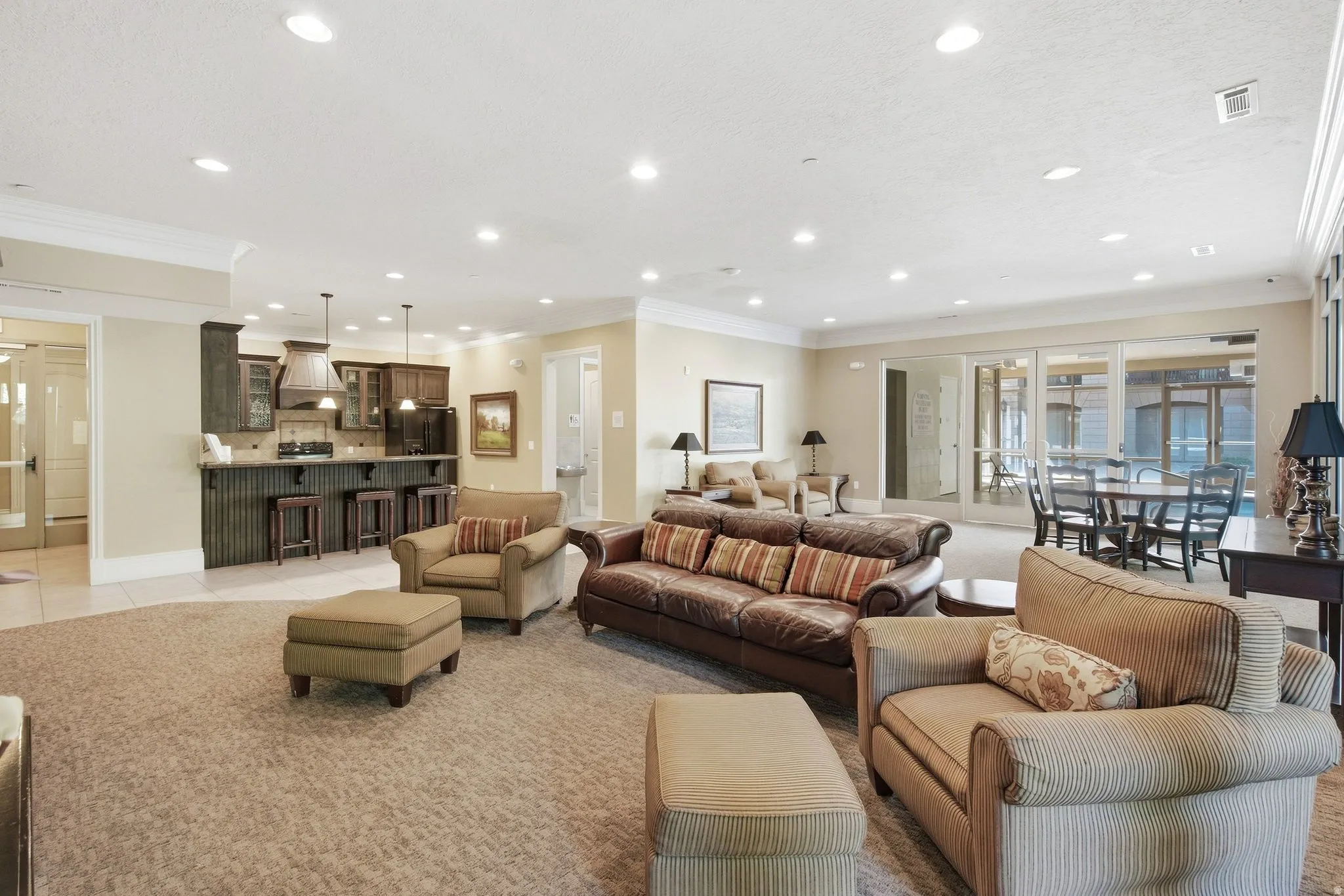 Recessed lighting, crown molding, built-in wet bar with cabinet storage, sliding glass doors, and carpet flooring