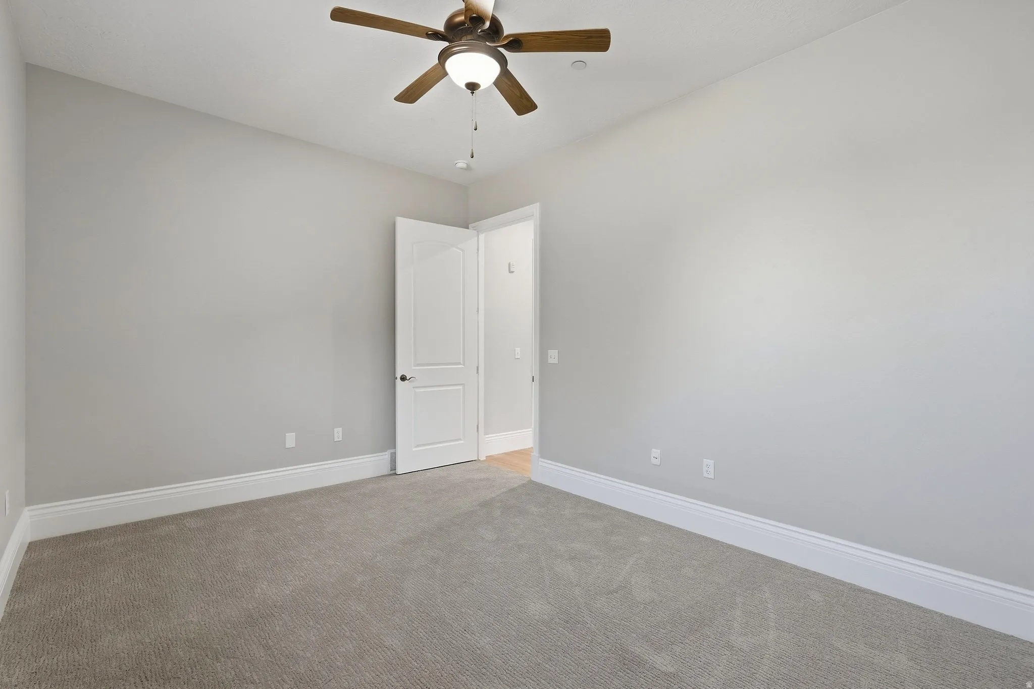 Carpeted room with light gray walls, white trim, and a ceiling fan with integrated lighting