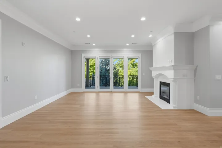 Hardwood-finish flooring throughout, featuring a white mantle fireplace with a dark-framed firebox