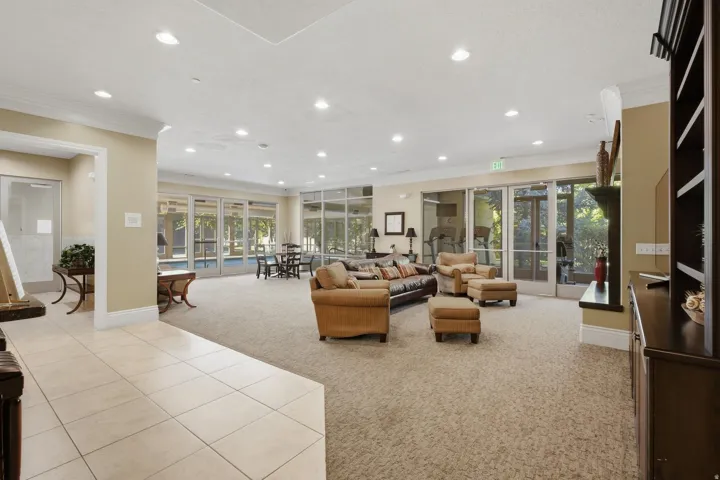 Expansive common area featuring recessed lighting, large format tile flooring, and direct access to an outdoor pool area through multiple glass panel doors