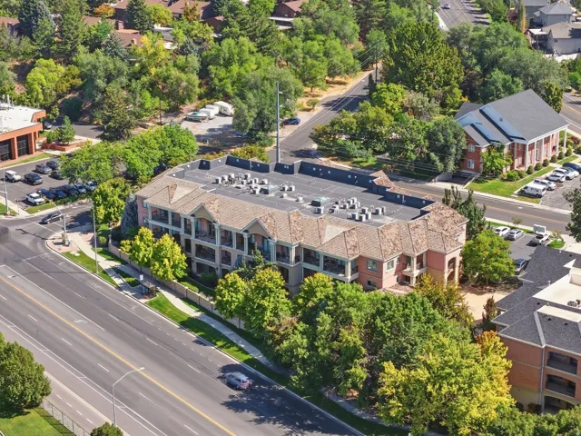 Multi-story building featuring balconies, a pitched roof, and visible rooftop units