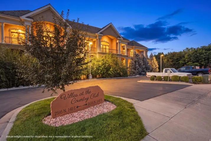 Stucco exterior with multiple balconies, paved parking area, and manicured landscaping