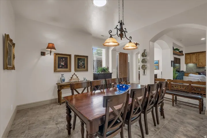 Recessed lighting, arched doorways, tiled flooring, built-in cabinetry, and a central chandelier