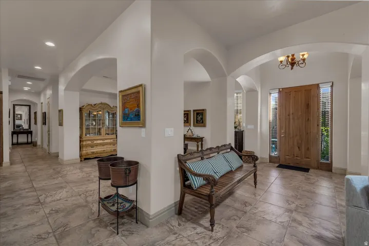 Arched interior passages, recessed lighting, tile flooring, wood-paneled entry door, and chandelier fixture
