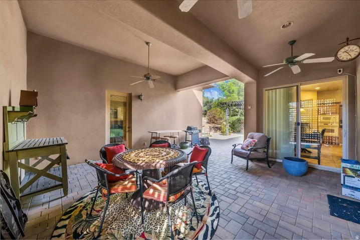 Covered patio with paver flooring, multiple ceiling fans, a sliding glass door, and an exterior door