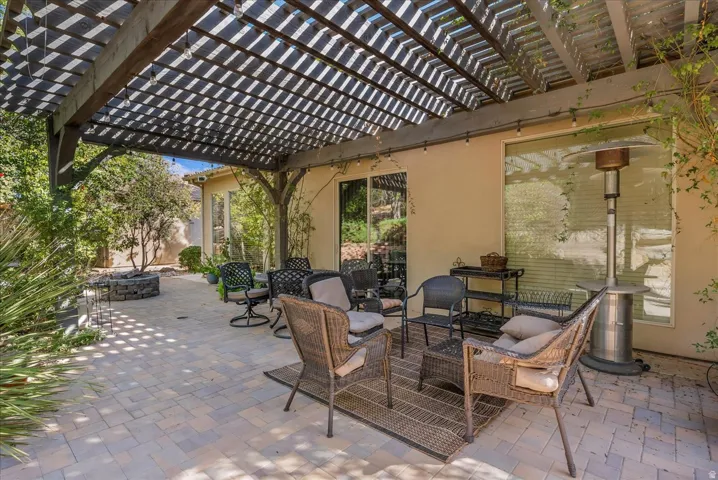 Wood pergola with lattice roof, paver patio, stone fire pit, and sliding glass door access
