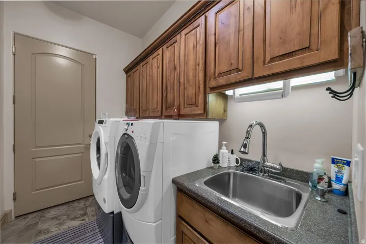 Wood-finish cabinetry, stainless steel sink, chrome faucet, and gray countertop