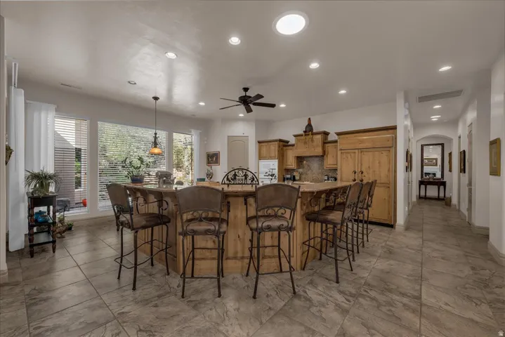 Spacious kitchen featuring a large island with seating, natural wood cabinetry, recessed lighting, and ample natural light from multiple windows