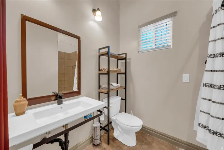 Bathroom featuring a rectangular vanity with a white basin sink, dark-finish faucet, and a wall-mounted mirror