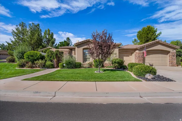 Stucco exterior with stone accents, tile roofing, an attached two-car garage, and a concrete driveway
