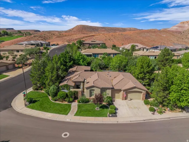 Property situated on a corner lot with an attached multi-car garage, mature landscaping, and a tile roof