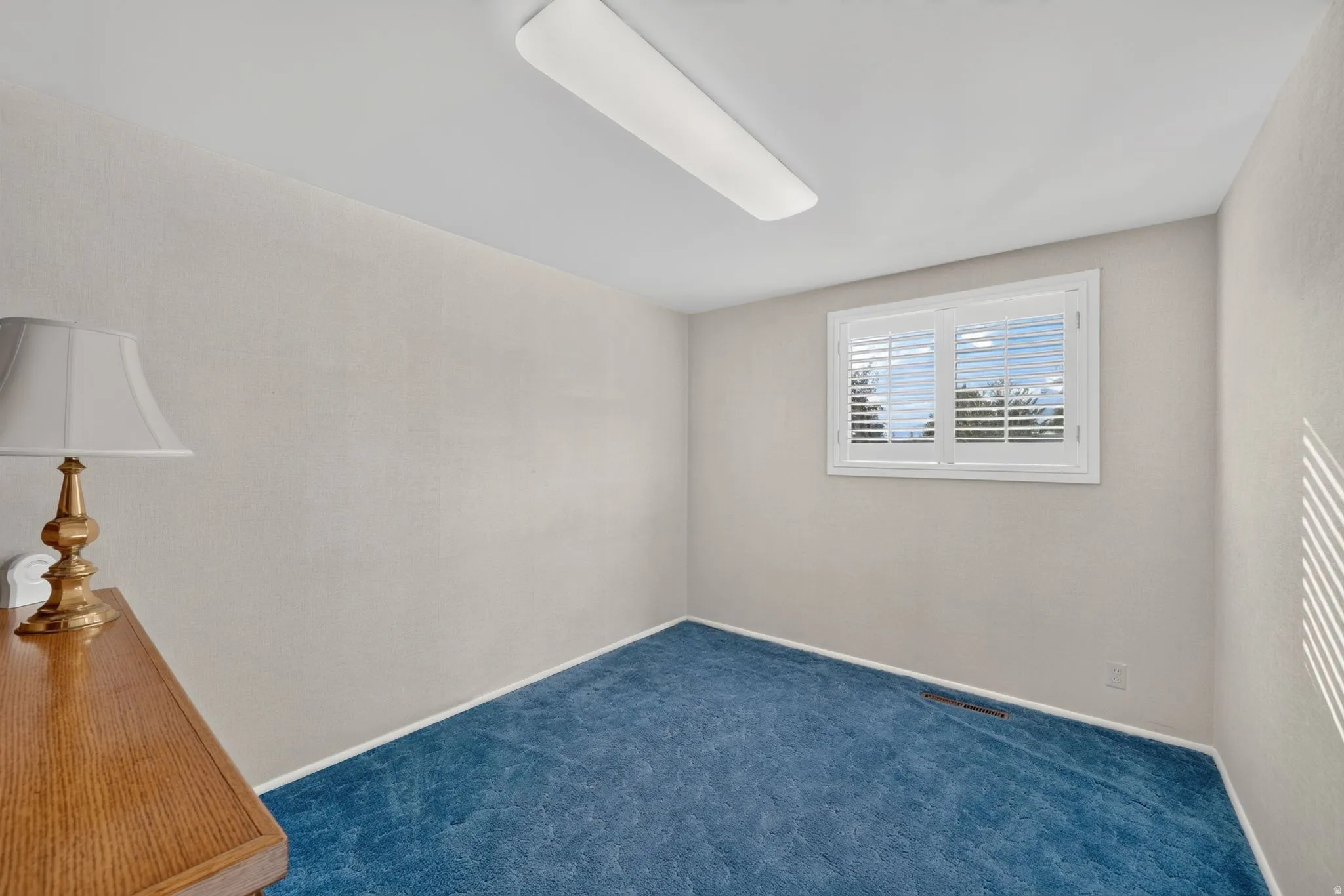 Recessed window with white plantation shutters, light-colored walls, and blue carpeting
