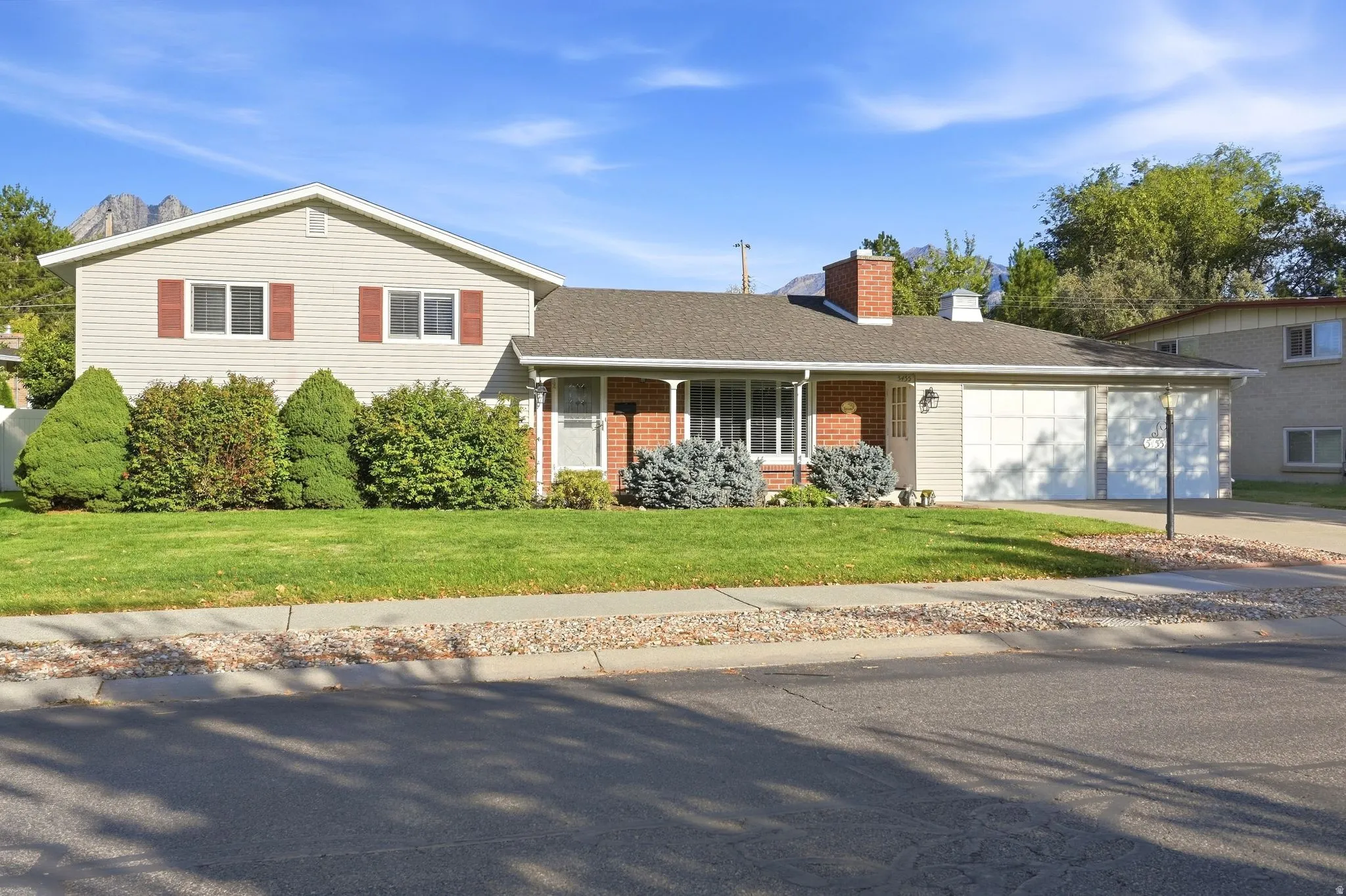 Two-story residence with a brick and siding exterior, featuring a two-car garage, mature landscaping, and an extended driveway