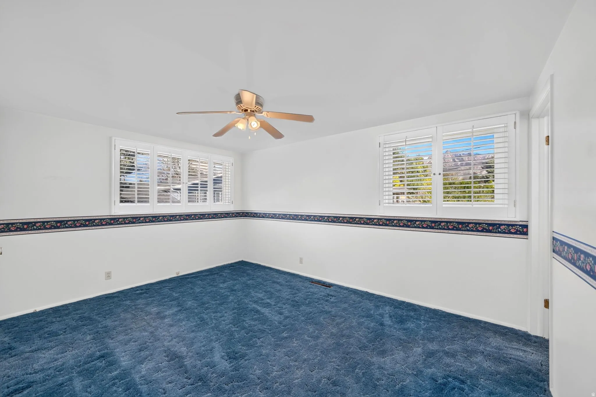 Recessed lighting, ceiling fan, white plantation shutters, carpeted flooring, and decorative wall border