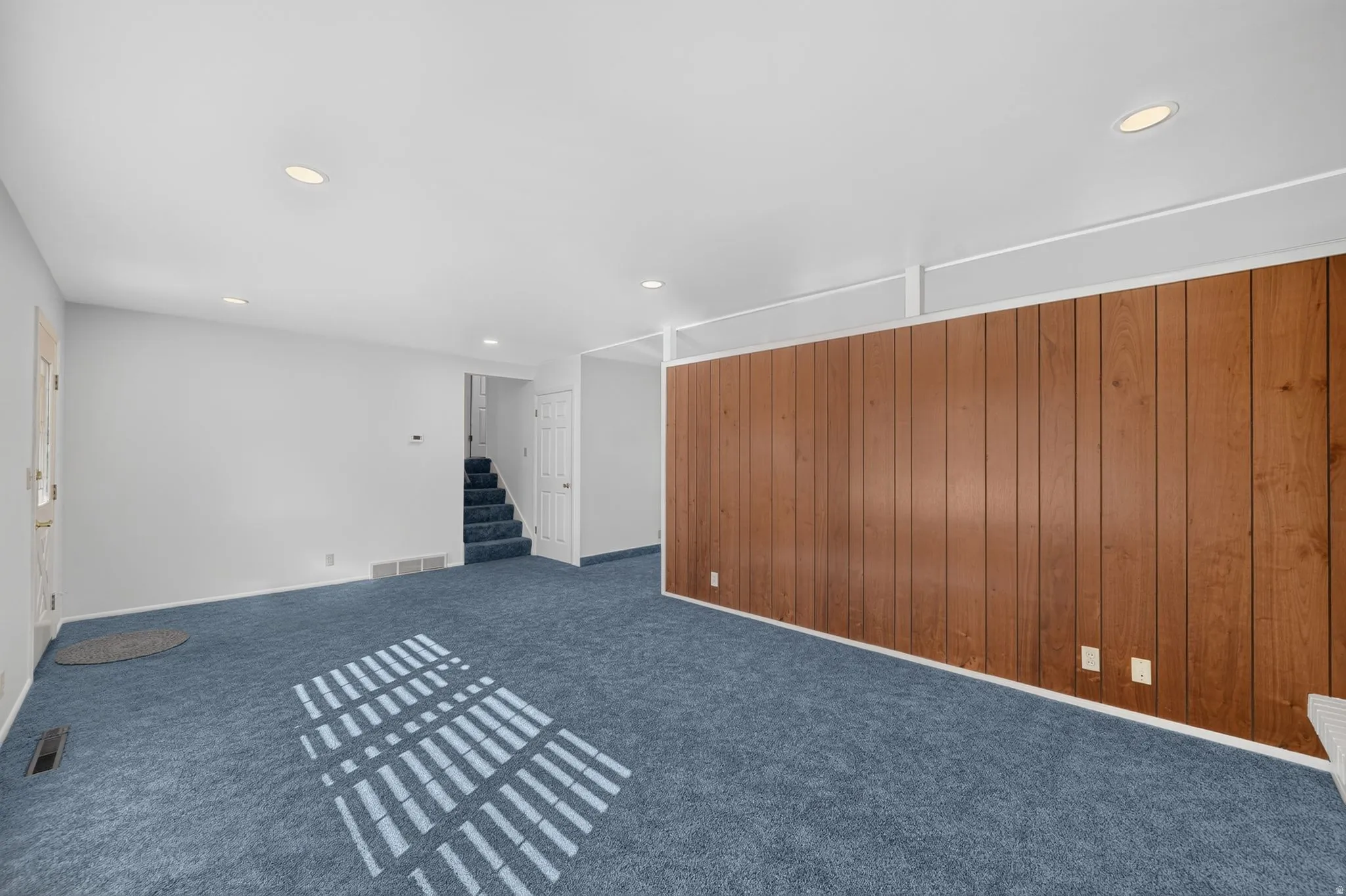 Spacious living area featuring recessed lighting, a paneled accent wall, and plush carpeting