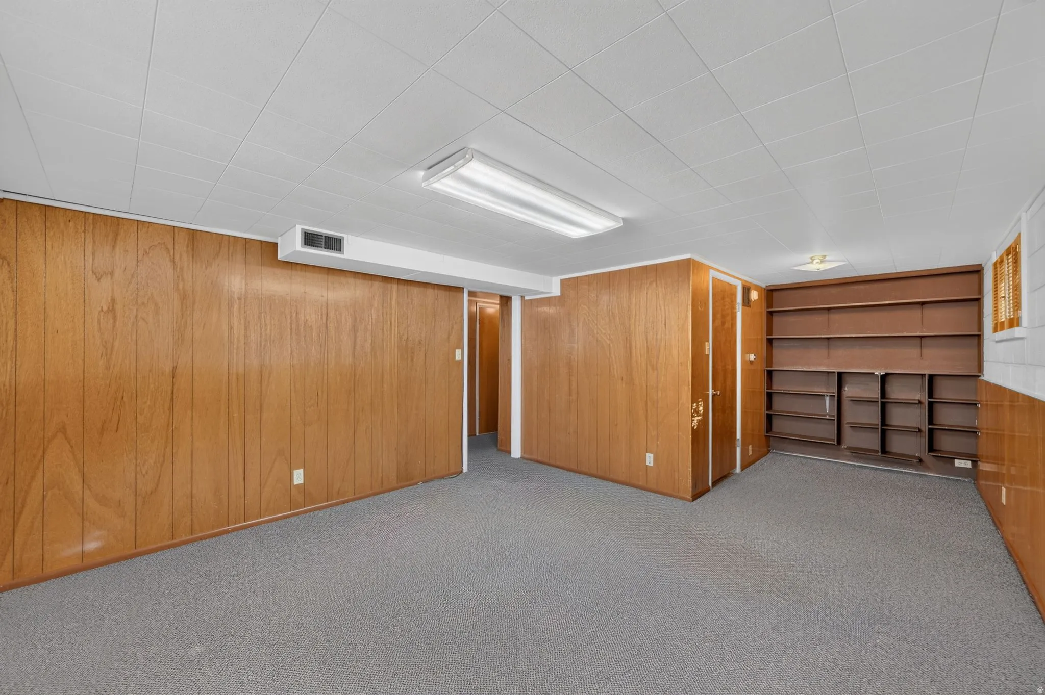 Carpeted flooring with wood-finish paneling and integrated shelving