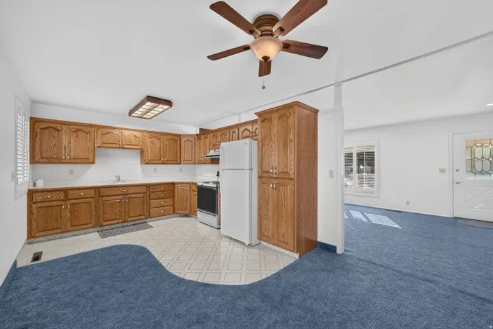 Kitchen featuring wood-finish cabinetry, white appliances, and a tile floor