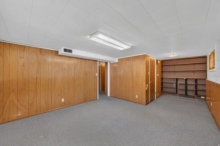 Carpeted flooring with wood-finish paneling and integrated shelving