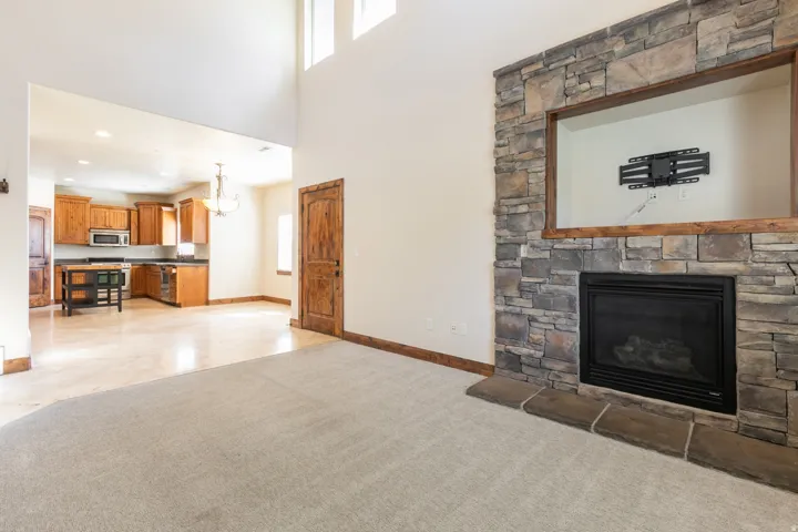 Stacked stone fireplace with hearth, built-in media niche, and high ceilings with upper windows