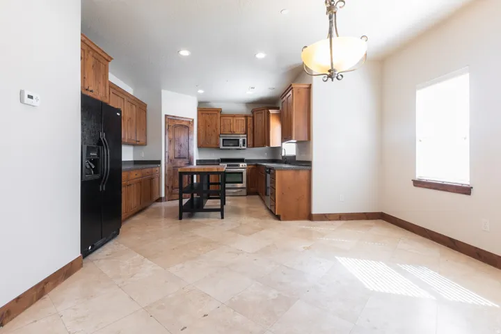 Kitchen with wood cabinetry, black appliances, dark countertops, and a wood island