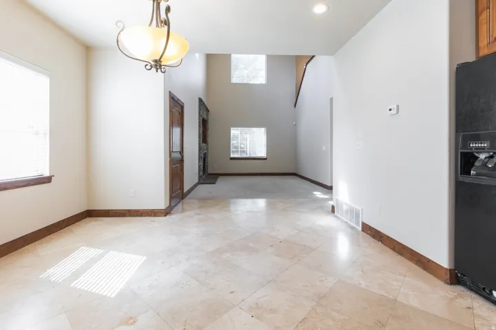Travertine tile flooring, wood-finish trim, chandelier lighting, wood-finish door, and recessed lighting
