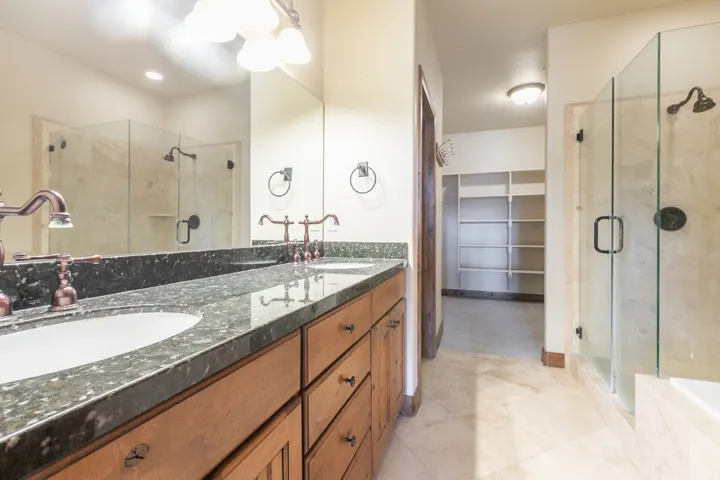 Dual vanity with granite countertop and copper-toned fixtures