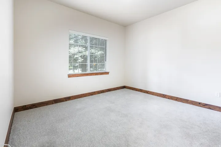 Light gray carpeting, white walls, and a window with blinds