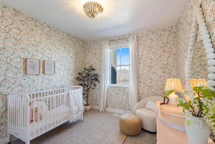 Room featuring botanical wallpaper, a single window with white trim, and a patterned area rug