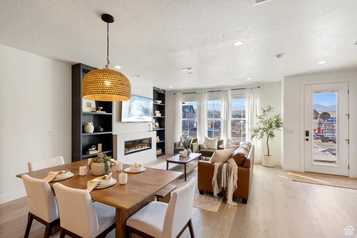 Open concept living area with light wood-finish flooring, recessed lighting, and a modern linear fireplace