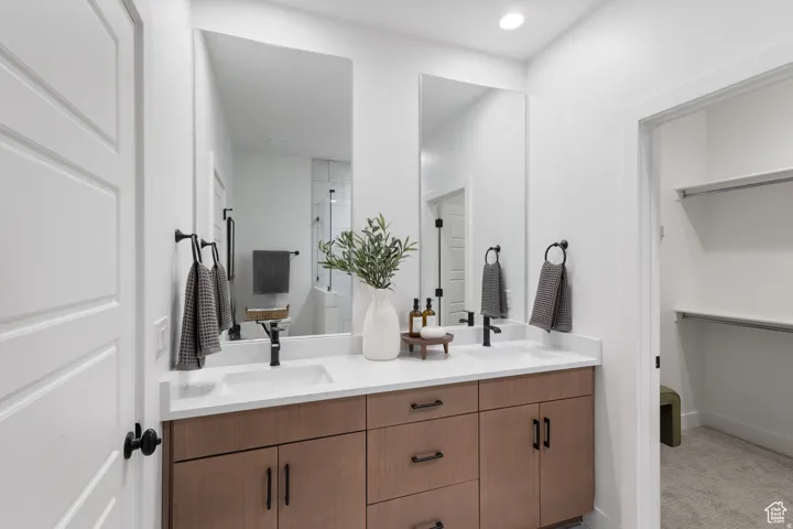 Double vanity with wood-finish cabinetry, white countertop, and matte black fixtures