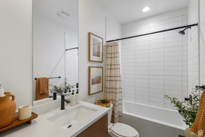 Bathroom featuring a built-in tub with tile surround, a single vanity with an undermount sink, and black hardware