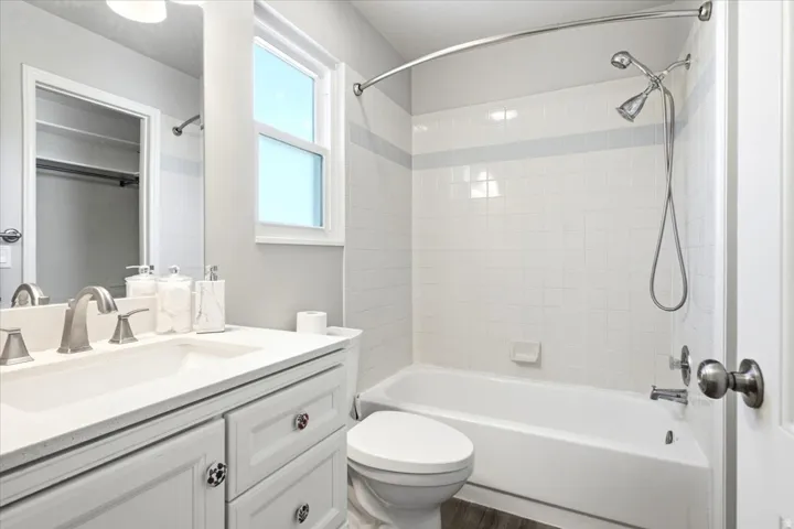 White vanity with a solid surface countertop, undermount sink, and brushed nickel faucet