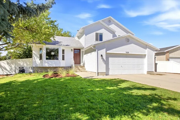 White siding exterior with a prominent two-car garage, a bay window, and a dark wood-finish entry door