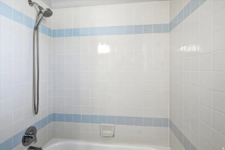 White tiled shower with a blue accent band