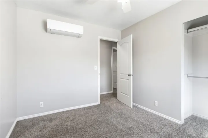Wall-mounted climate control unit, overhead ceiling fan, and carpeted flooring